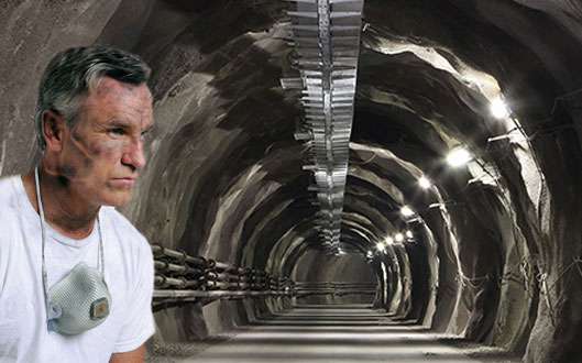 man standing in front of tunnel with face mask around neck